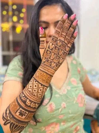 This design showcases a variety of textures, from the bold lotus motifs at the top to the fine jaal pattern covering the hand.