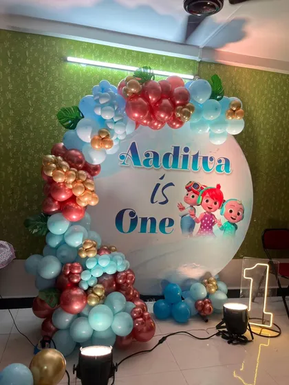 This Cocomelon theme is a favorite for first birthdays. The setup includes a custom circular backdrop with the birthday boy's name, a vibrant balloon garland, and a light-up marquee number '1' to make the milestone special.