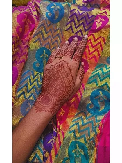 A simple heart-shaped mandala design on the back of the hand. The stain is still light here, as it was recently applied.