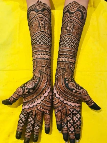 This engagement mehendi is all about intricate patterns and clean lines. The design uses a mix of checkered fills, paisleys, and floral bands to create a full and luxurious look.