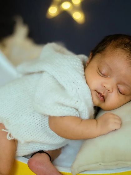 This detailed photograph captures the peacefulness of a newborn's sleep. The soft knit romper adds a lovely texture to the image.