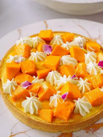 Another take on the mango tart, this time with delicate cream piping and edible flowers. This highlights our ability to capture fine details and create exceptionally pretty food visuals.