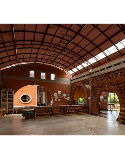 The interior of the learning center is characterized by repeating arches and circular openings. These architectural elements create a sense of rhythm and flow, making the large space feel both cohesive and full of interesting nooks to explore.