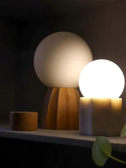 The warm glow of our custom lamps against a dark shelf. The contrast of light and dark, and the simple geometric forms of the fixtures, create a composition of elemental shapes.