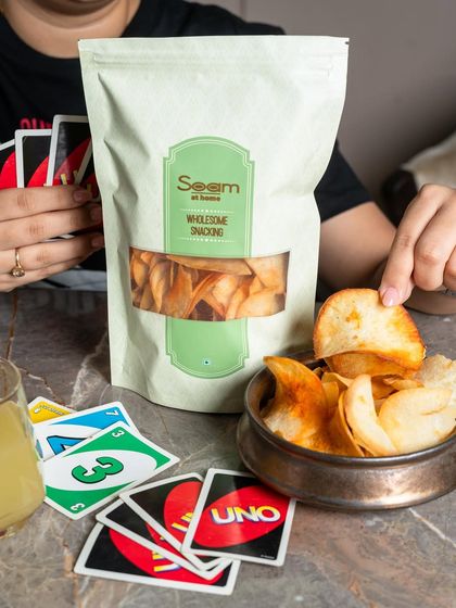 Plot twist: you can win at UNO and snacks. My Masala Ratalu Chips are shown as the perfect gaming partner, adding spice to a fun game night.