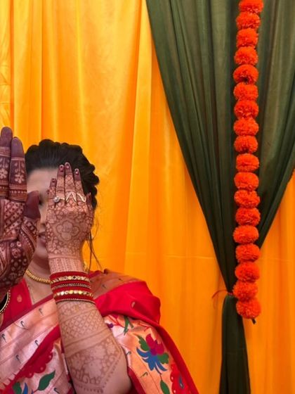 A classic bridal pose showcasing the intricate henna work on both the front and back of the hands, extending up the arms for a complete look.