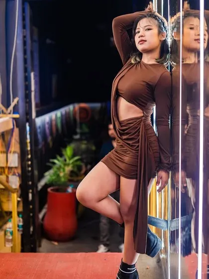 A guest in a stunning brown dress, posing against the reflective walls.