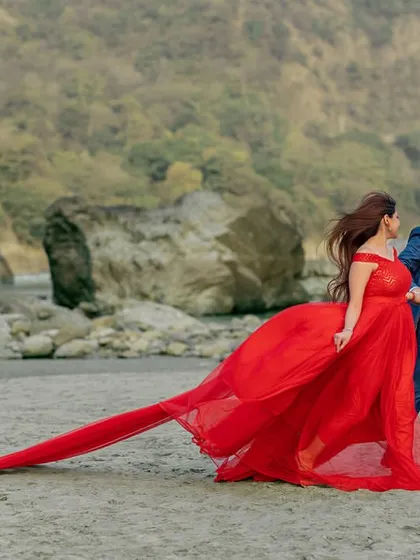 A playful run along the beach, with the long trail of the red gown following behind. This candid action shot combines the elegance of the gown with a sense of fun and adventure.