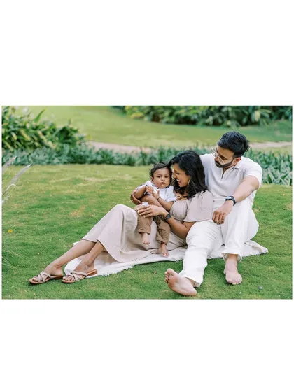A wide shot of the family enjoying a picnic-style setup for their son's first birthday, showing the relaxed vibe of an outdoor shoot.