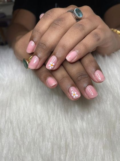 A simple pink gel polish manicure on natural nails with cute, hand-painted daisy accents.