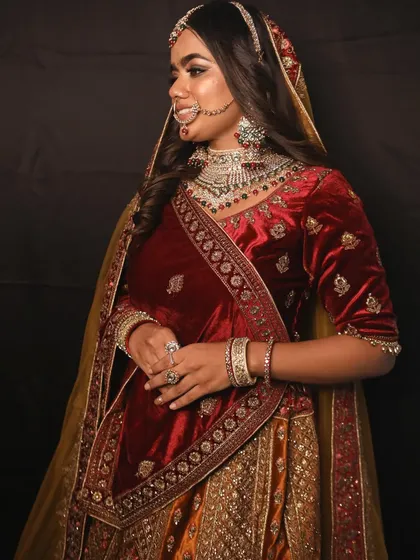 A beautiful shot showing the combination of the velvet lehenga, heavy jewellery, and the bride's happy expression.