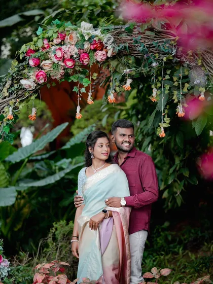 A couple poses under a rustic floral arch, a beautiful and natural frame for their portrait.