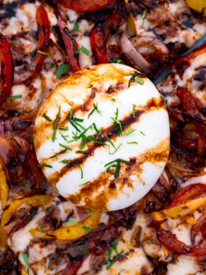 A top-down shot of the burrata pizza, showing the beautiful arrangement of colors from the peppers and the perfectly grilled cheese. Great for menus.