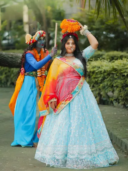 A playful, full-length shot of Radha and Krishna, showing the complete costumes and interaction.