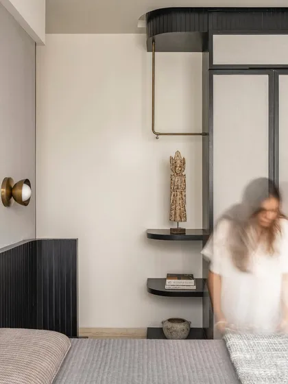 This bedroom in Apartment 3201 evokes a stately, masculine calm with its monochrome palette and black fluted paneling. We introduced hints of brass and found artifacts to create a subtle feminine balance within the young couple's suite.