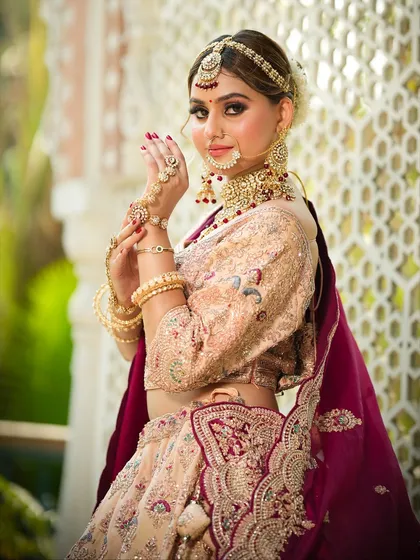A graceful side profile of the bride, showcasing her elaborate jewelry and the flawless airbrush finish of her makeup.