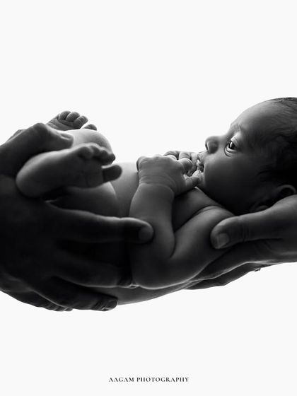 A variation of the "in your hands" pose, this time with the baby awake and looking up at their parents.