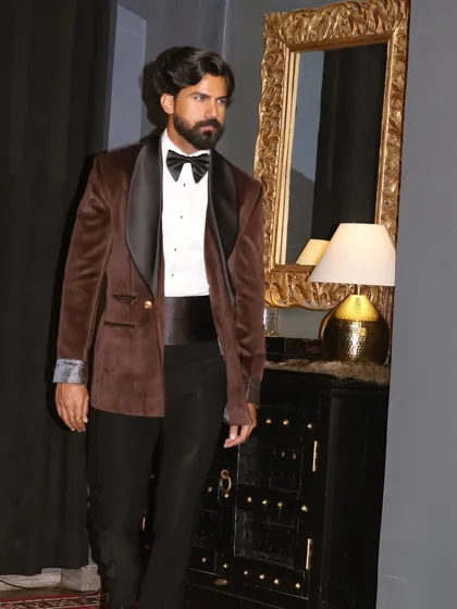 The rich texture of the brown velvet tuxedo is evident in this shot, complete with a traditional cummerbund.