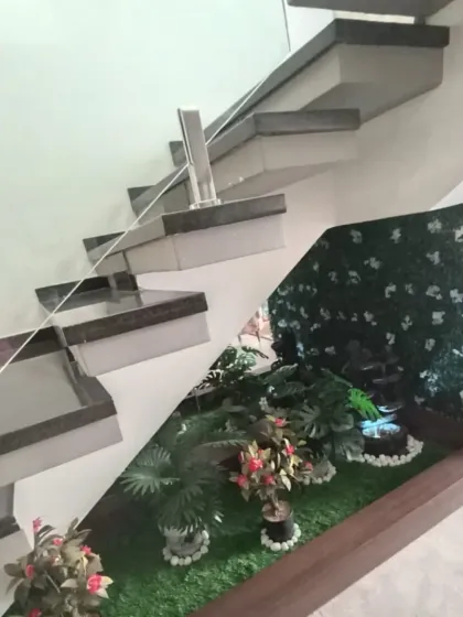 I make use of every corner. Here, I've converted the awkward, unused space under a modern staircase into a beautiful, low-maintenance artificial garden, complete with faux plants, a small water feature, and a green wall backdrop.
