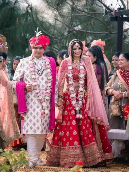 The couple's walk together after the varmala ceremony. This candid shot captures their first steps as husband and wife, surrounded by the love and joy of their family.