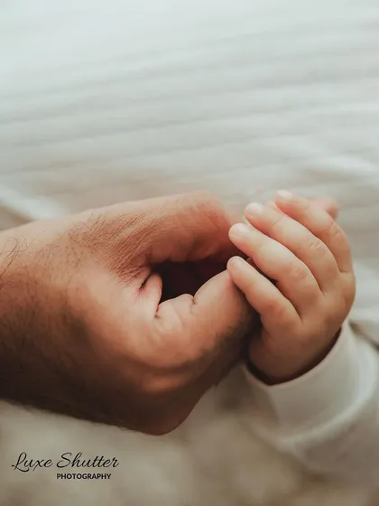 A close-up of a baby's hand gently holding their parent's finger, a simple and classic shot full of meaning.