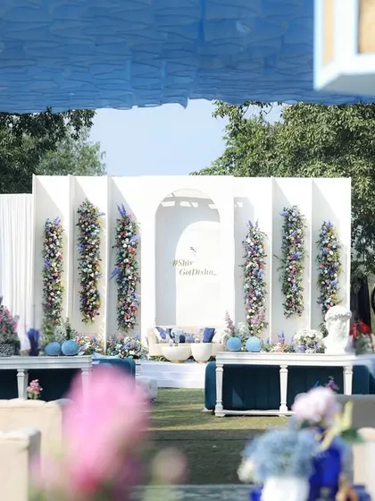 A wide view of the blue and white stage, framed by the blue-draped canopy of the outdoor tent.