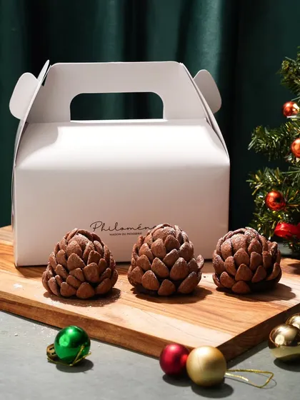 Simple, elegant, and festive. These pinecone-shaped desserts are presented with a clean, branded takeaway box and subtle Christmas decorations, highlighting them as a perfect holiday gift.