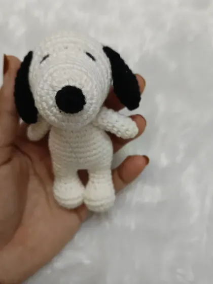 Holding one of the cute Snoopy toys to show its pocket-friendly size. It's a perfect little handmade accessory for any fan.