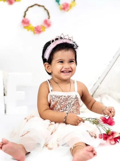 Before the cake smash begins, we take time to capture beautiful, clean portraits. This shot shows a happy one-year-old in our studio, showcasing her personality with a bright smile before the messy fun starts.