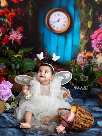 Looking up in wonder, this little butterfly fairy is absolutely captivating. The colorful, flower-filled backdrop creates a vibrant and joyful scene.