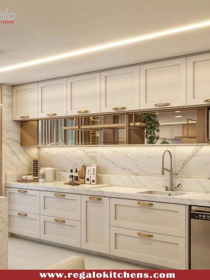A beautiful kitchen design featuring white shaker-style cabinets, a marble backsplash, and gold hardware. The reflective gold inlay adds a touch of glamour and luxury.