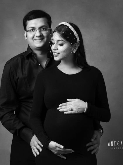 A close-up black and white portrait of an expecting couple. Her serene expression and his proud smile are beautifully captured.