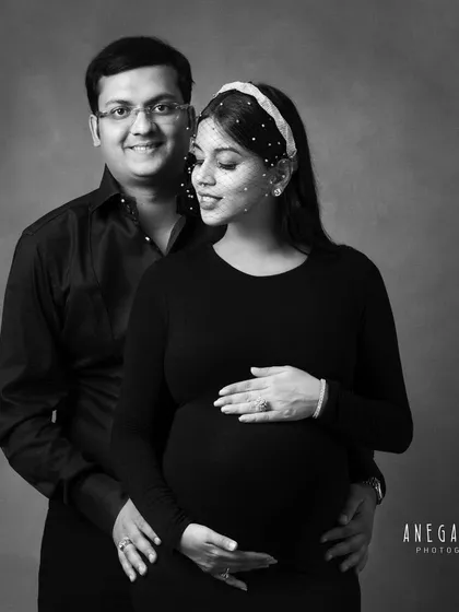 A classic and elegant black and white portrait. The formal attire and soft lighting create a sophisticated and timeless image for this expecting couple.