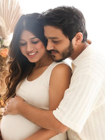 A tender embrace from behind, with both parents' hands on the baby bump. This pose beautifully symbolizes the protective and nurturing love surrounding their unborn child.