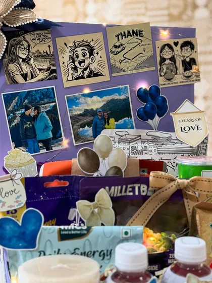 The collage of memories, including photos from their travels and cute illustrations, serves as the backdrop for this thoughtful anniversary hamper.
