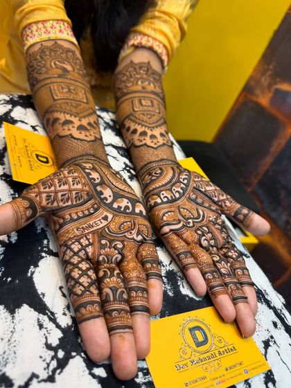 An elegant engagement design with the groom's name, 'Sanket', written on the palm. The design includes elephant motifs and traditional jaali work.