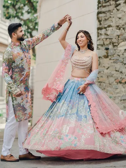 The couple shares a dance during their Mehendi ceremony, with the bride's colorful lehenga twirling beautifully. A perfect capture of pre-wedding happiness.
