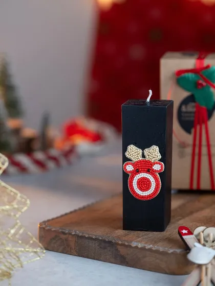 A cute reindeer embellishment on a black pillar candle. The contrast is striking and adds a modern touch to the holiday theme.