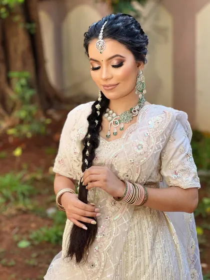 A close-up of the bride holding her braid, giving a better view of the pastel green necklace and matching earrings.