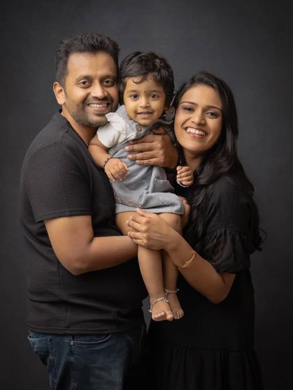 A happy family of three in a classic studio portrait. The coordinated black outfits give this image a sleek and modern feel.