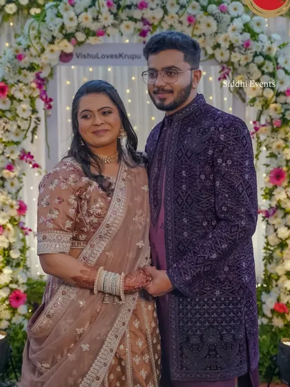 The happy couple posing within the custom floral Instagram frame, a perfect example of how we personalize decor to create lasting memories.