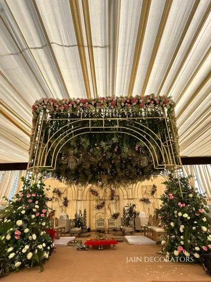 A wide view of the floral canopy mandap, showing how it commands the space. The structure is supported by pillars of flowers, creating a cohesive and immersive garden setting for the wedding.
