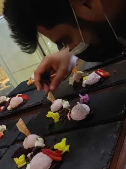 Our chef carefully plating desserts with fresh strawberries and edible flowers. Precision and artistry are key when preparing for a formal sit-down dinner service.