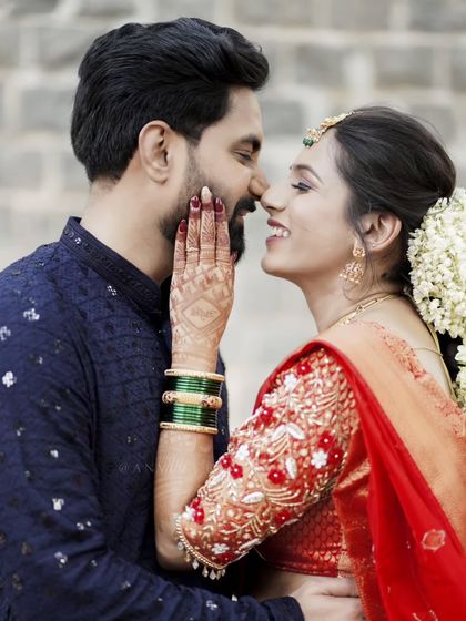 A playful and intimate moment, capturing the bride's beautiful smile and henna-adorned hand.