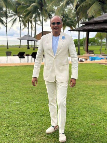 Another shot of the custom off-white suit, showing its relaxed yet sharp silhouette against a beautiful outdoor backdrop. This is what bespoke resort wear looks like.