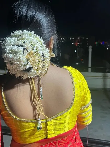 A detailed look at the back of the hair, showing a beautiful bun completely covered in fresh white flowers (mogra), a classic element of a bridal look.