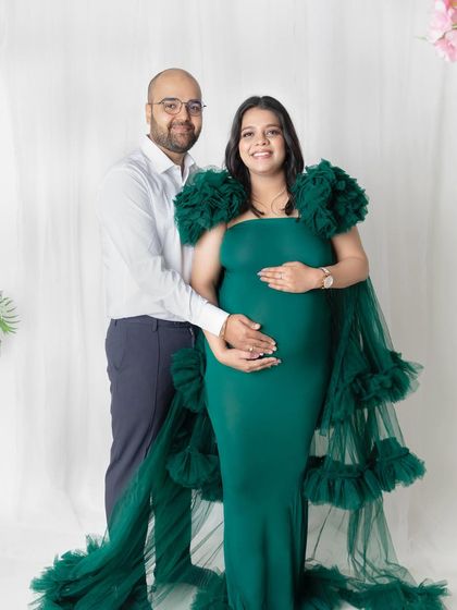 A classic couple portrait for your maternity album. The partner stands supportively behind the mom-to-be, both gently holding the baby bump. It’s a timeless pose that symbolizes unity and anticipation.