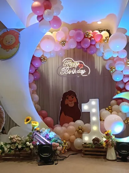 I can bring any cartoon theme to life for your child's first birthday. This grand Lion King setup includes character cutouts, a large crescent moon prop, a light-up number '1', and a custom neon 'Happy Birthday' sign.