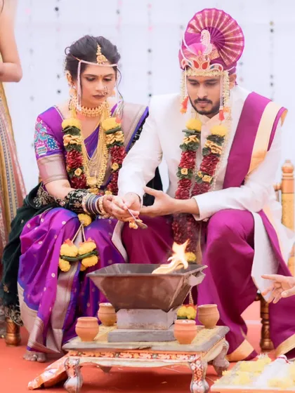 A candid shot from a Maharashtrian wedding ceremony. The bride's makeup is designed to be long-lasting and photogenic, even during the most important rituals.
