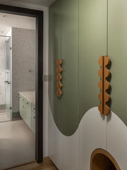 A view from the bedroom into the kids' bathroom, showing the custom wavy-paneled wardrobe with unique wooden handles, creating a cohesive and imaginative space.